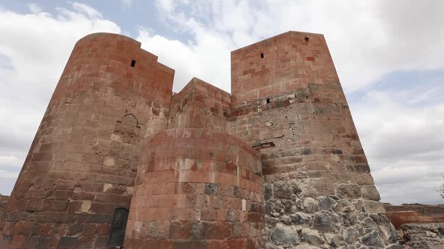 Discover the majestic ruins of Dashtadem Fortress in Armenia. The video showcases the medieval architecture, prominent red tuff stone walls, and a beautiful ancient archway against cloudy skies.

