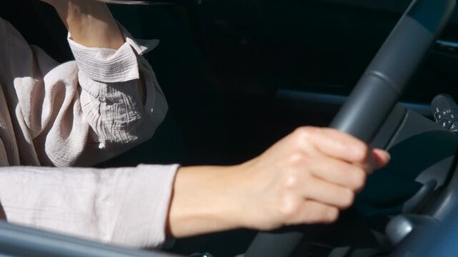 Woman drinking alcohol while driving a car. Close-up of a business woman opening a bottle of wine or champagne while driving her car, concept of driving under the influence of alcohol