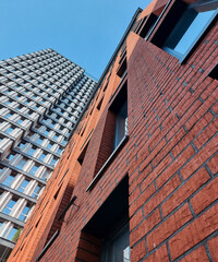 Looking up at the facade of modern building with brick facade. Stylish residential building on sunny day against clear blue sky. 