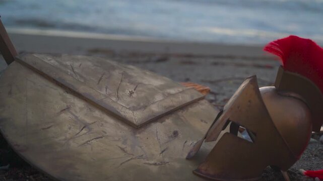 an ancient battlefield at sunset, a Spartan sword, shield, and helmet on the ground