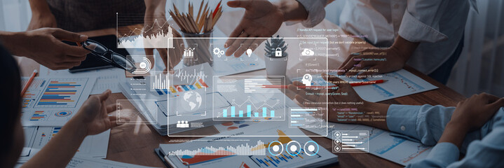 Fototapeta premium A business team engages in discussion while analyzing financial data through modern digital interfaces and charts in a contemporary office environment. Trope
