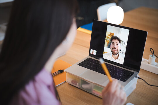 A woman is on a video call with a man, both are smiling and engaged in conversation.