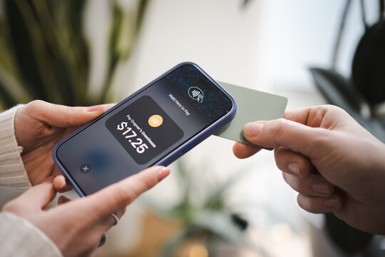 A person uses a smartphone to pay for a purchase of $17.25 at a greenhouse using contactless technology.