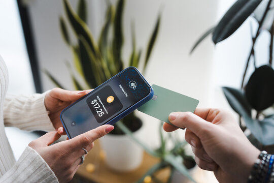 A person uses a smartphone to make a contactless payment of $17.25 for a purchase at a greenhouse.
