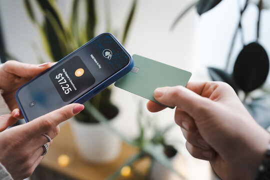 A person uses a smartphone to make a contactless payment with a card.