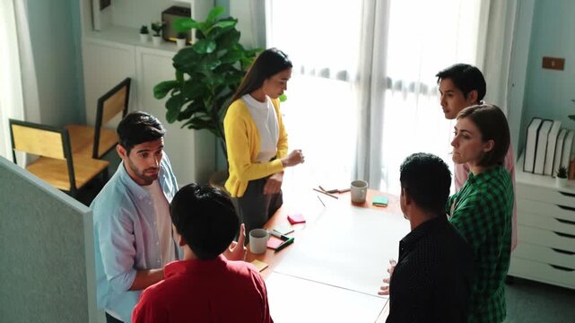 Group of diverse people discussing about marketing plan at meeting. Top view of smart manager talking and sharing creative idea while male leader standing at blackboard and present plan. Convocation.