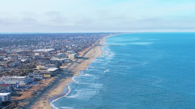 Kill Devil Hills, North Carolina, aerial cinematic video of the Atlantic coastline featuring sandy beaches, vacation homes, and the expansive Outer Banks landscape.