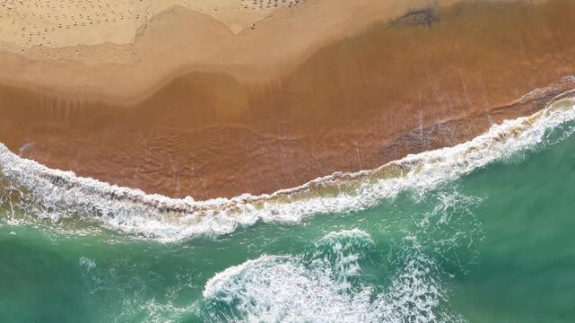 Kill Devil Hills, North Carolina, a top-down aerial view of turquoise Atlantic waters crashing against a sandy beach shoreline with tire tracks on the Outer Banks.