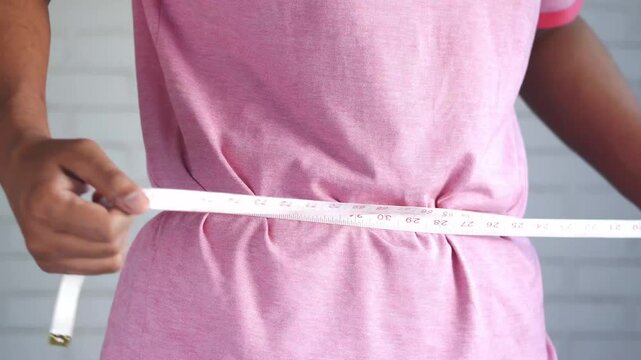 Person measuring waist with tape measure, health and fitness concept, close-up
