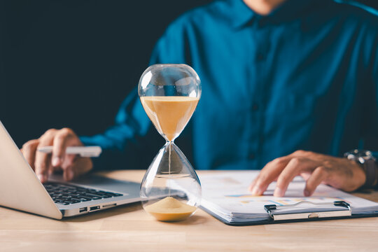 Hourglass time pressure on business document management, professional busy with financial work, meeting tight deadline, focusing on reports, analyzing data with laptop
