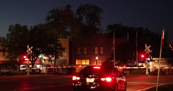 Evening traffic and a freight train pass through historic downtown Delhi, Louisiana, USA.