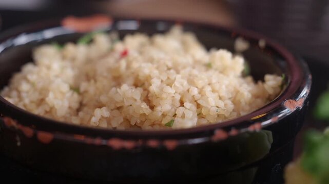 Close up shot of cooked quinoa in a black bowl with fresh herbs and garnish