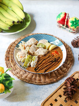 A plate of Sundanese cuisine&mdash;known as siomay Bandung or baso tahu&mdash;is set on a placemat. The dish includes boiled potatoes, fish dumplings, tofu, bitter melon, and a rich peanut sauce.