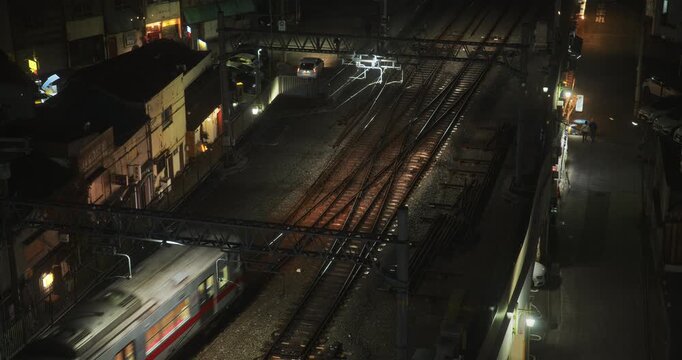 High, still shot over tracks and glowing Japanese train traveling across