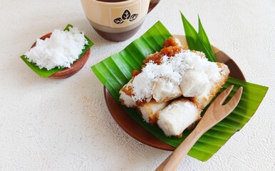 Traditional Indonesian kue putu served on banana leaf with grated coconut and palm sugar sauce. Popular as takjil or sweet snack for iftar during Ramadan. Authentic Southeast Asian dessert