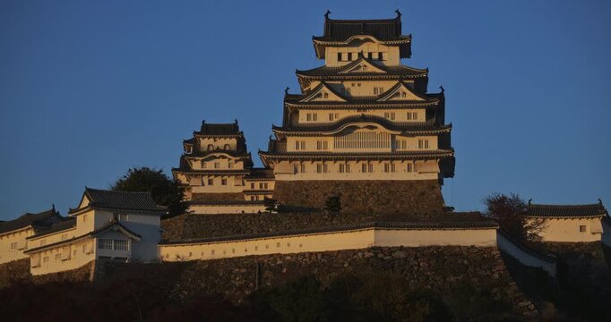 Beautiful, wide shot of orange glow on tall 16th century Japanese castle