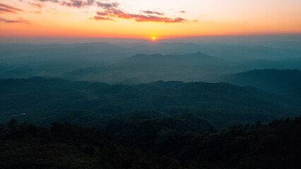 Breathtaking aerial landscape of layered mountains silhouette at golden hour sunset.