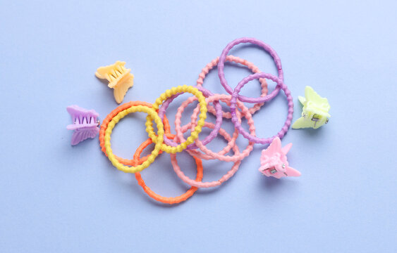 Colored hair ties and clips on a pastel blue background