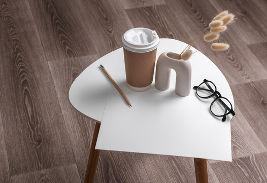Blank paper sheet with pensil and vase with dry grass, eyeglasses on coffee table. Business concept. Top view.