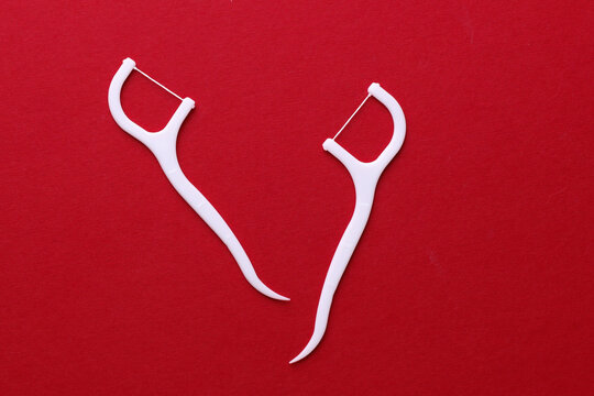 Floss toothpicks on red background. Dental hygiene concept. Top view