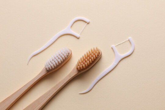 Wooden Toothbrushes and floss toothpicks on beige background. Dental hygiene concept. Top view