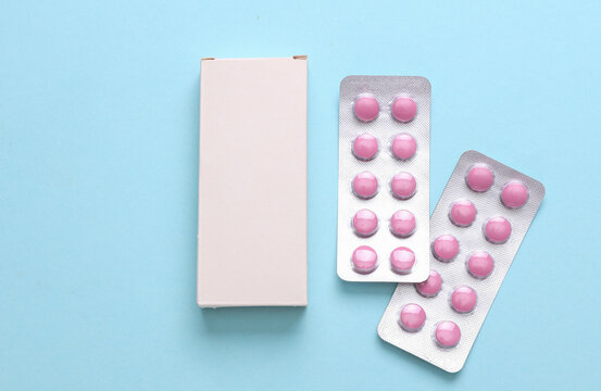 Blister packs of pills with blank white box on a blue background. Medicines, medical concept. Design mockup. Creative layout. Flat lay.