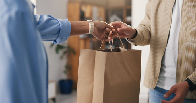 Hands, paper bag and people in boutique, business owner and discount deal with purchase. Employee, consumer and customer in store, giving and retail for shopping spree, spending and checkout service