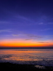 Stunning vibrant sunset over the calm ocean with a striking purple orange and pink twilight sky © Hamid