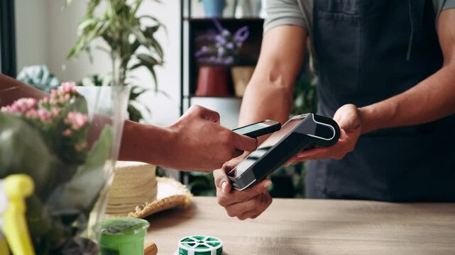 Video of close up of woman hand paying for the purchase with her smartphone via NFC in a flower shop