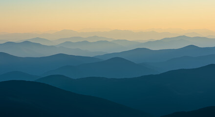 Fototapeta premium A serene mountain landscape at dusk with layered hills and a warm sky.
