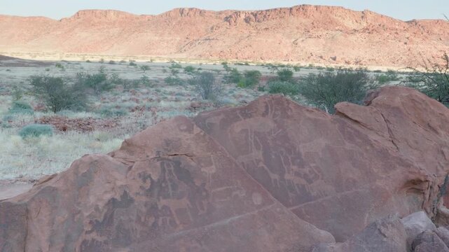 a wide panning shot of african rock art of various animals and symbols at twyfelfontein in namibia, africa