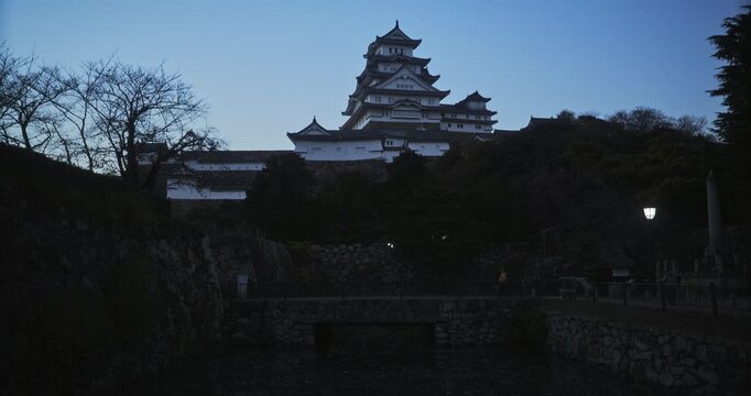 Majestic, wide silhouette of 16th century Matsumoto castle and stone walls at dusk