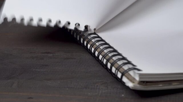 Close-up hand tearing sketchbook paper along the spiral