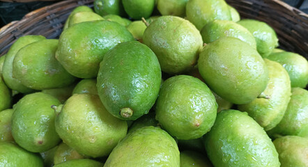 A close up view of a woven basket filled with fresh green bilimbi fruits