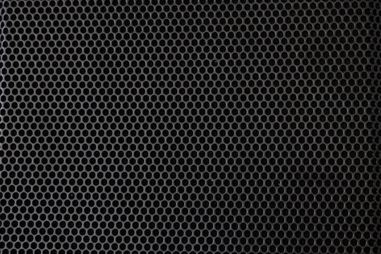A close up of a black metal surface with many small holes