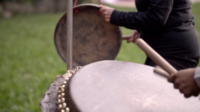 Close-up of people playing traditional drums outdoors, rhythmic and lively