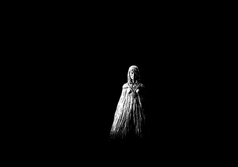 Mysterious woman in a long dress standing alone.