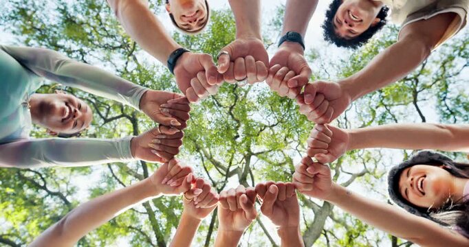Low angle, fist bump and people in forest, smile and team building for support. Below, friends and men with women, celebration and gesture for unity, motivation and collaboration for group activity
