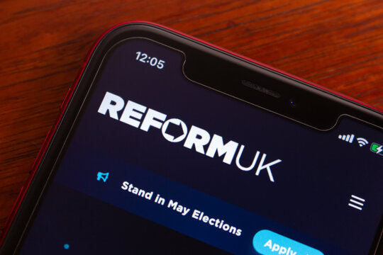 Quito, ECUADOR - Feb 18 2026 : Close-up of a smartphone displaying Reform UK political website header and apply button, on wooden table for election campaign.