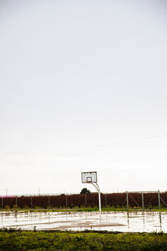 Rustic basketball hoop on empty outdoor court in rural field