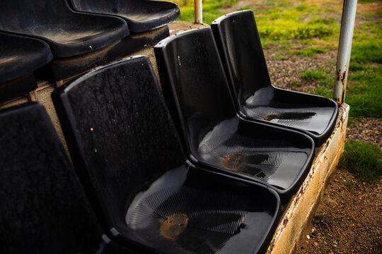 Black plastic stadium seats wet with rain and dirt stains
