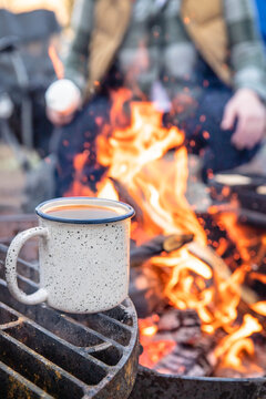 Mug of coffee warming on campfire grill camping