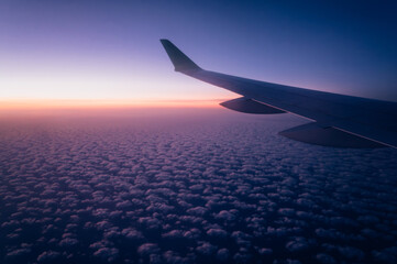 Fototapeta premium Airplane Wing Over Clouds at Dawn with Pink Horizon – Window Seat