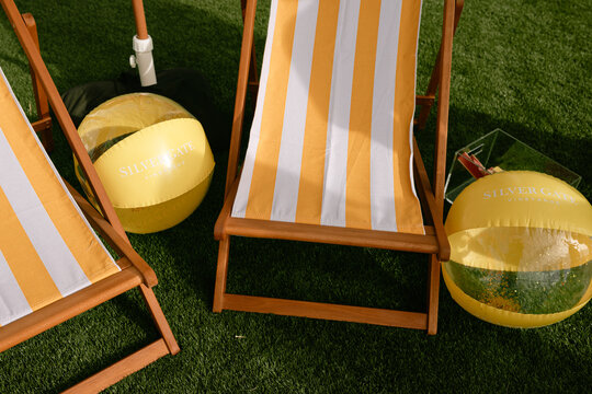 Yellow striped deck chairs beside umbrella on green lawn