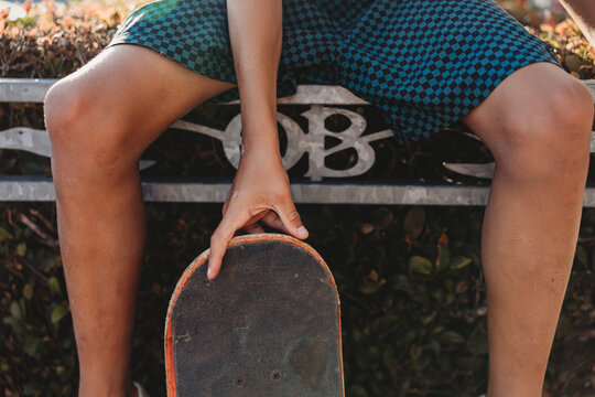 Boy sitting on an OB sign holding the top of his skate board.