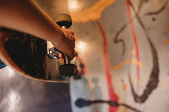 Detail shot of a boy holding his skateboard.