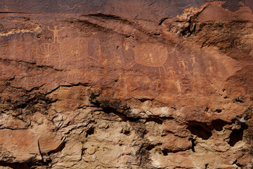 Fototapeta premium Petroglyphs of animals and figures on brown stone face