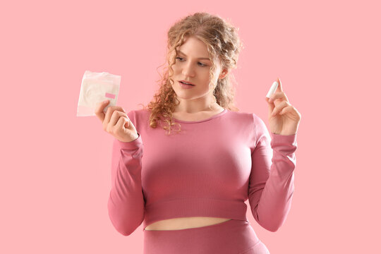 Female trainer with tampon and menstrual pad on pink background