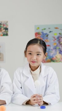 Young Asian Girl in Lab Coat Performs Bernoulli Principle Science Experiment