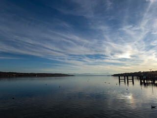 Obraz premium Wide lake view with distant alpine mountains and soft evening glow